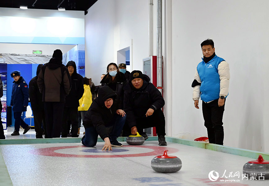 首届呼伦贝尔·海拉尔冰雪产品冬季展销会现场，游客正在尝试投冰壶。人民网记者 刘艺琳摄