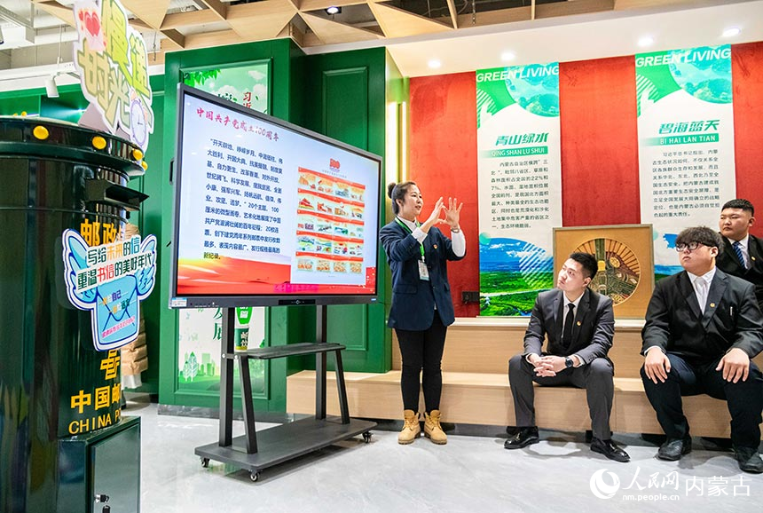 邮政工作人员在内蒙古建筑职业技术学院“思成建院邮局”红色实训课堂为同学们讲解邮票背后的故事。丁根厚摄
