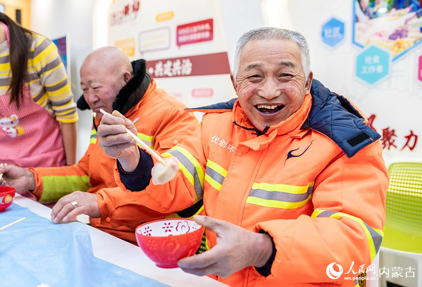 环卫工人在呼和浩特市玉泉区兴隆巷街道清泉街社区品尝冬至饺子。丁根厚摄