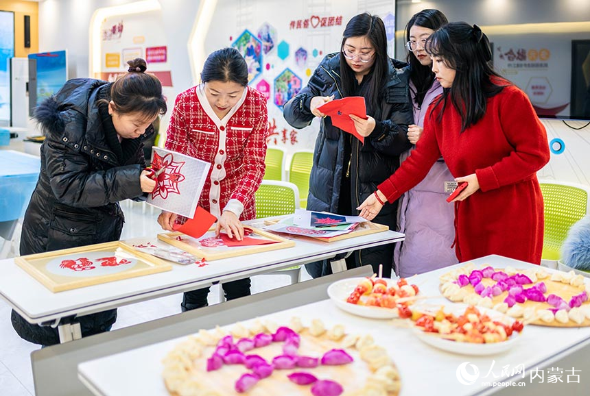 呼和浩特市玉泉區興隆巷街道清泉街社區志願者在制作窗花剪紙。丁根厚攝