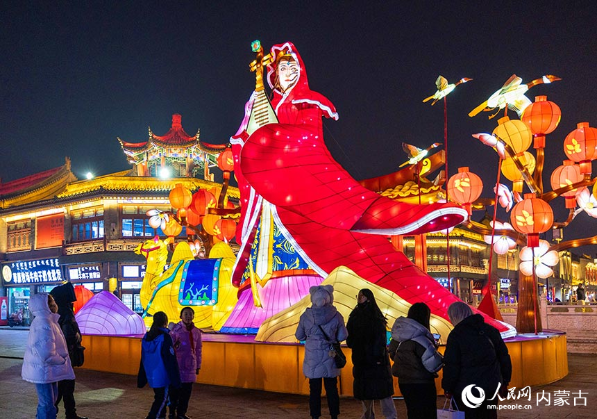 游人在呼和浩特市玉泉区塞上老街旅游休闲街区“昭君出塞”灯组前打卡拍照。丁根厚摄