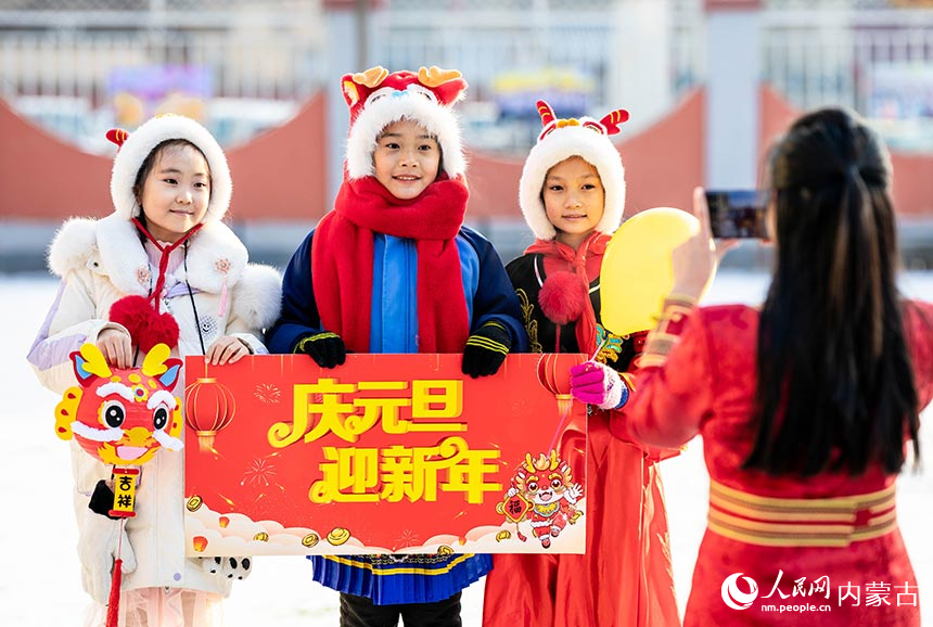 呼和浩特市玉泉区南柴火市街小学学生手持“庆元旦 迎新年”字样拍摄创意合影。丁根厚摄
