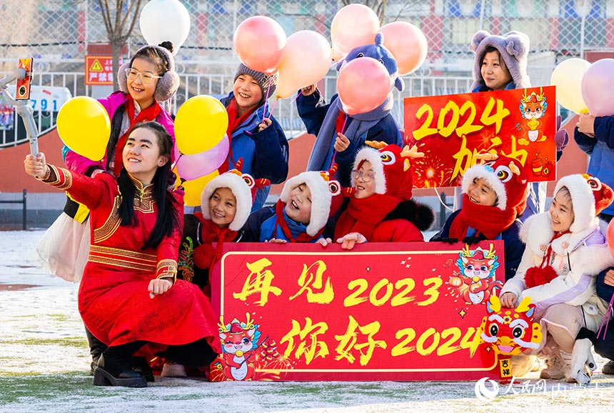 呼和浩特市玉泉区南柴火市街小学学生手持“再见2023 你好2024”字样和老师合影。丁根厚摄