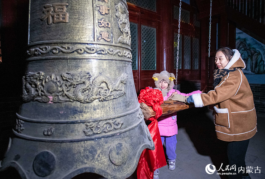 2023年12月31日，游人在呼和浩特市玉泉区塞上老街旅游休闲街区钟鼓楼撞钟迎新年。丁根厚摄