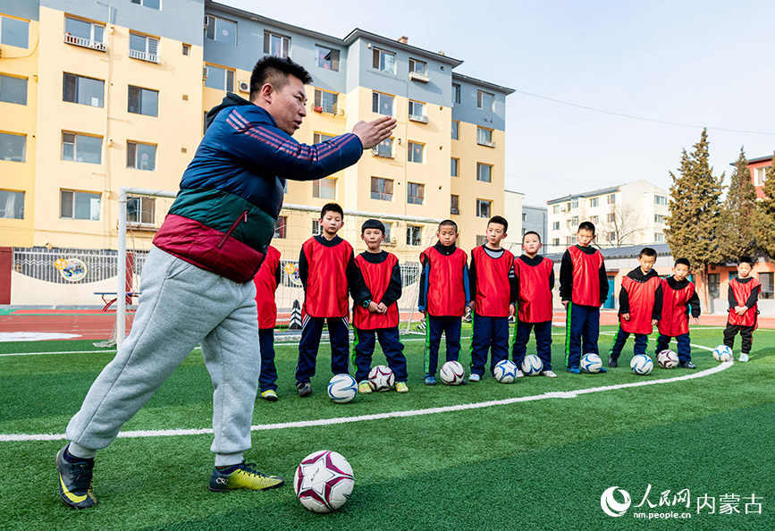 2024年1月8日，呼和浩特市玉泉區南茶坊小學的足球教練為小球員做傳接球示范。丁根厚攝