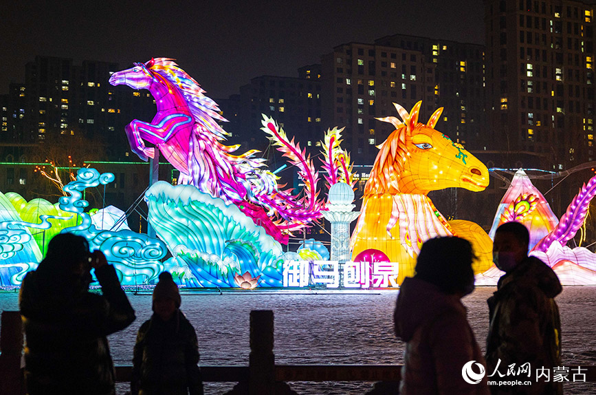 2024年1月18日,游客在呼和浩特市玉泉区小黑河花灯展《御马刨泉》主题灯组前打卡拍照。丁根厚摄