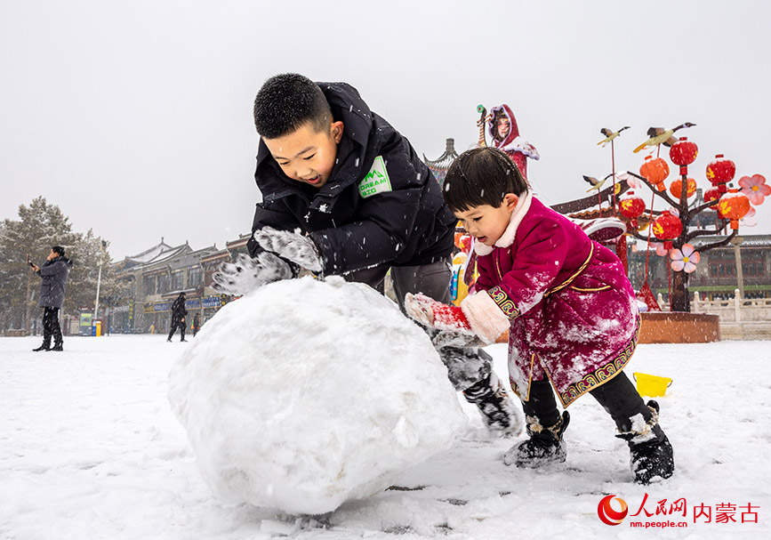2024年1月19日，小朋友冒雪在呼和浩特市玉泉区塞上老街旅游休闲街区滚雪团。丁根厚摄