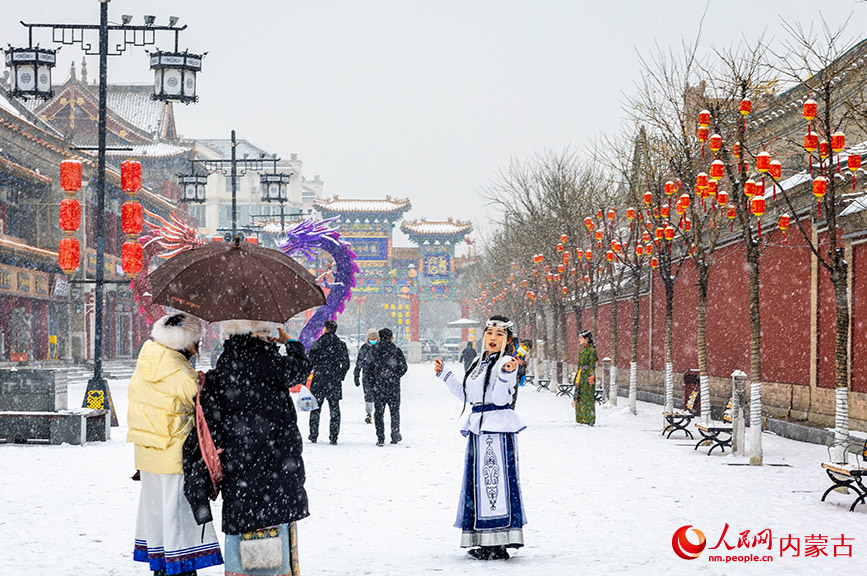 2024年1月19日，游人冒雪在呼和浩特市玉泉区塞上老街旅游休闲街区打卡拍照。丁根厚摄