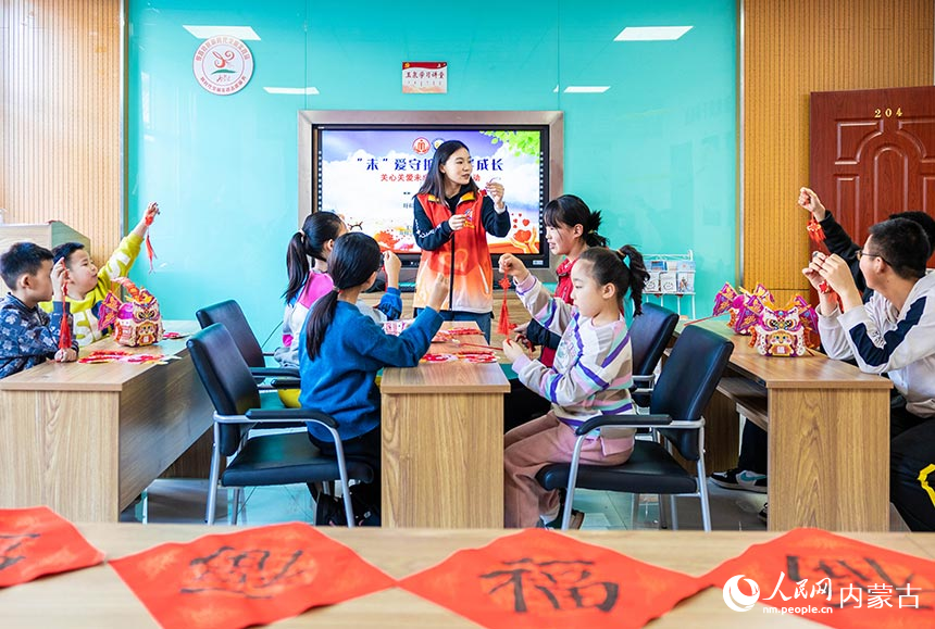 志愿者在“品传统年韵 迎龙年新春”主题活动现场给孩子们讲授中国结编织技艺。丁根厚摄
