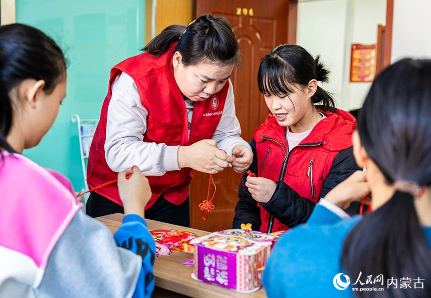 志願者在“品傳統年韻 迎龍年新春”主題活動現場教孩子們編織中國結。丁根厚攝