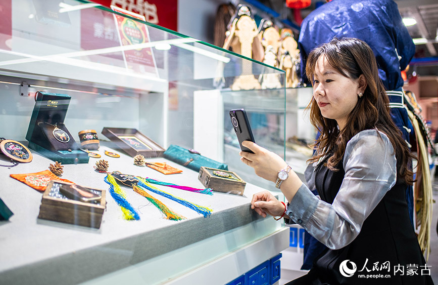 2024年1月27日，市民游客在第七屆內蒙古非遺年貨節現場拍攝烏拉特刺繡展品。丁根厚攝