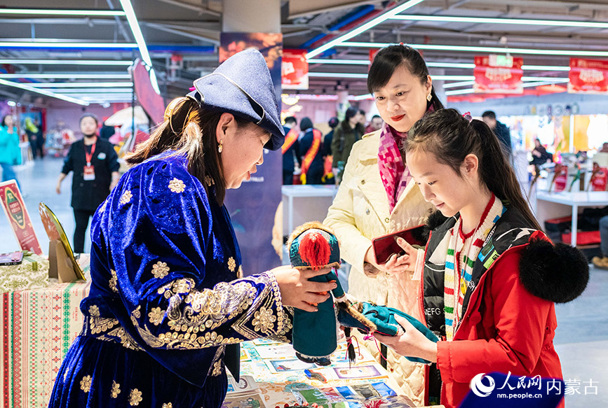 2024年1月27日，家長陪伴孩子在第七屆內蒙古非遺年貨節現場選購布裡亞特娃娃。丁根厚攝