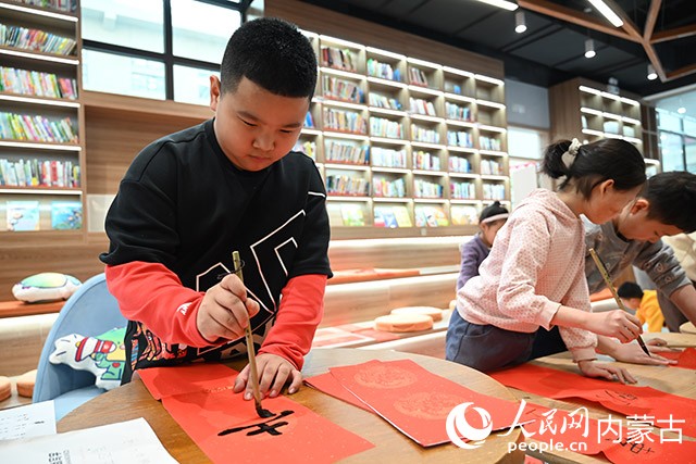 康巴什區青春山街道神華康城社區“青苗學社”內，小朋友正在寫春聯。人民網記者 劉藝琳攝