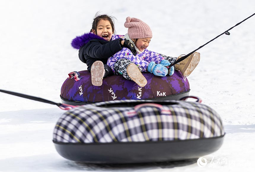 小朋友在内蒙古呼和浩特市青城公园公益冰场玩雪圈。丁根厚摄