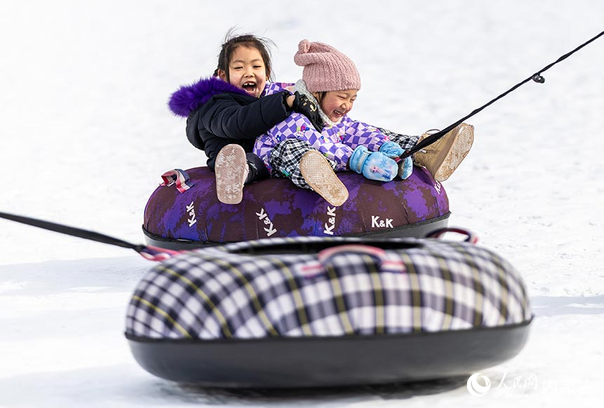 小朋友在內蒙古呼和浩特市青城公園公益冰場玩雪圈。丁根厚攝