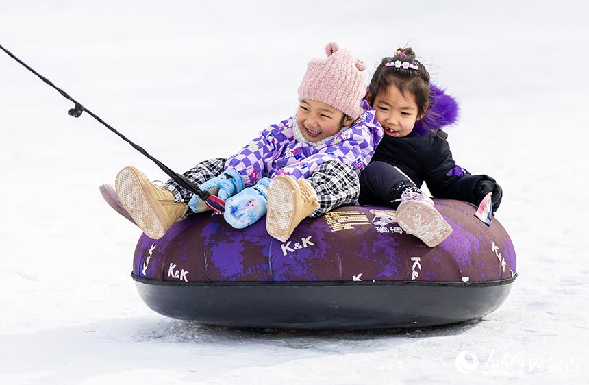 小朋友在內蒙古呼和浩特市青城公園公益冰場玩雪圈。丁根厚攝
