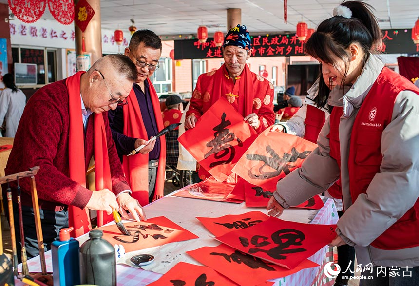 志愿者在呼和浩特市玉泉区民政局“福至养老院 情暖夕阳红”迎新春活动现场为老人书写中国“福”和寿字。丁根厚摄