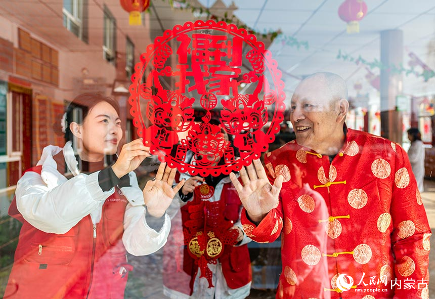 志愿者和老人在呼和浩特市玉泉区玉泉区夕阳红老年康乐园内张贴迎新春饰品。丁根厚摄