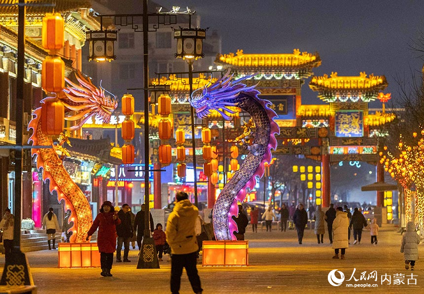 游人在呼和浩特市玉泉区塞上老街旅游休闲街区观赏双龙造型的灯组。丁根厚摄