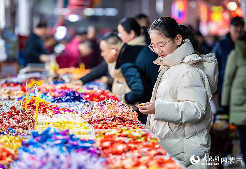 顾客在呼和浩特市玉泉区美通批发市场年货节上选购糖果。丁根厚摄