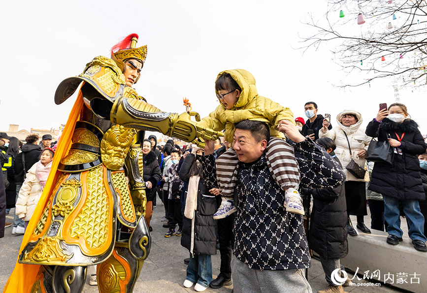 2月24日，游人在呼和浩特市玉泉区塞上老街旅游休闲街区与国风机甲互动。丁根厚摄