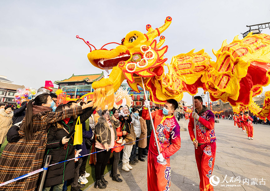 2月24日，舞龙艺人在呼和浩特市玉泉区塞上老街旅游休闲街区民俗展演活动中与游人互动。丁根厚摄