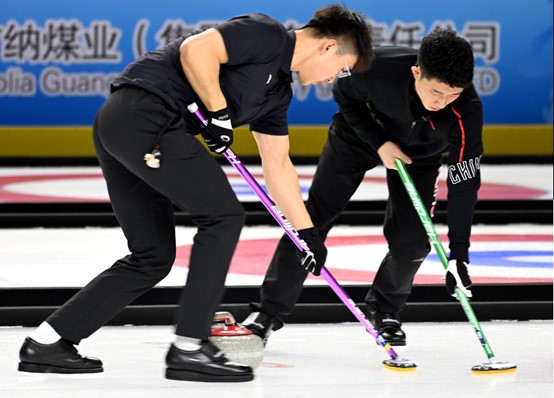 2月26日，河北队选手费学清（右）和队友李智超在冰壶公开组男子金牌赛中擦冰。曹政摄