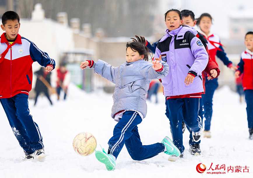 2月27日，孩子们在呼和浩特市玉泉区石东路小学校园雪地趣味足球赛比赛中拼抢。丁根厚摄