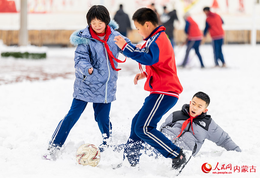 2月27日，孩子们在呼和浩特市玉泉区石东路小学校园雪地趣味足球赛比赛中拼抢。丁根厚摄