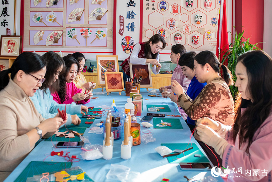 3月6日，呼和浩特市玉泉區南柴火市街小學女教師在體驗皮藝挂件制作技藝。丁根厚攝