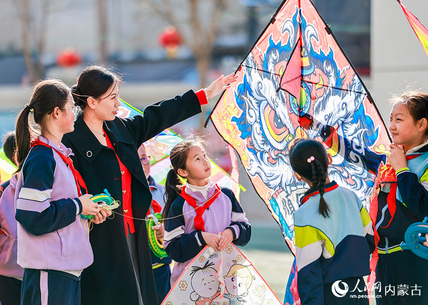 3月13日，呼和浩特市玉泉區恆昌店巷小學老師在給學生講解風箏的飛行原理。丁根厚攝