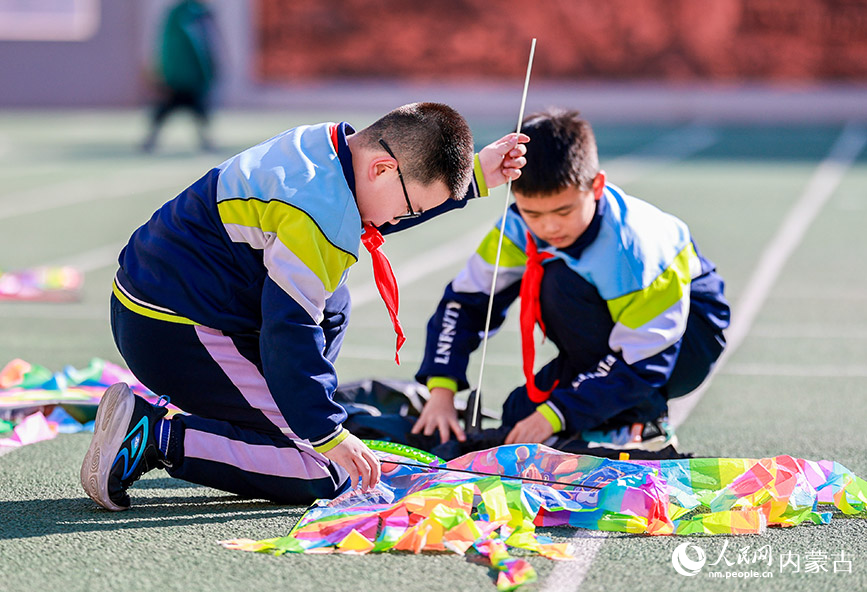 3月13日，呼和浩特市玉泉區恆昌店巷小學學生在操場上組裝風箏。丁根厚攝
