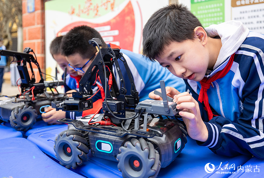 3月27日，呼和浩特市玉泉区清泉街小学学生在观看工程机器人的构造。丁根厚摄