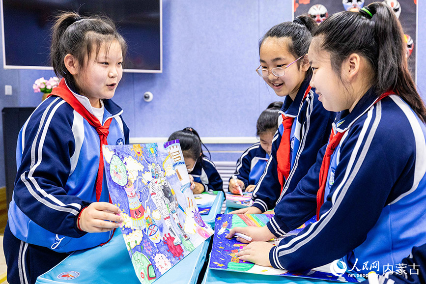 3月27日，呼和浩特市玉泉区清泉街小学学生向伙伴展示绘制的科学幻想画。丁根厚摄