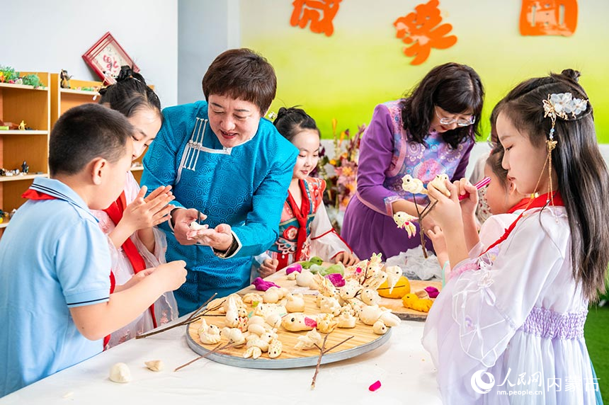 呼和浩特市玉泉区通顺街小学学生在老师的指导下学习制作面塑寒燕。丁根厚摄