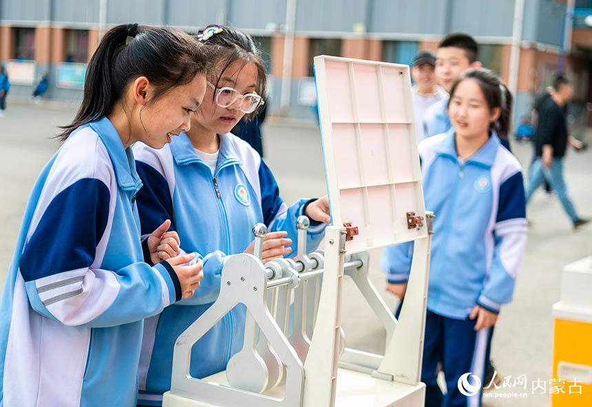 内蒙古呼和浩特市第二十七中学学生在“科技大篷车”进校园活动现场体验科普展品“磁力传动摆”。丁根厚摄