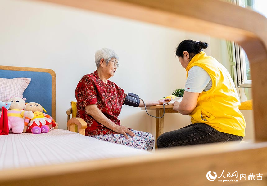 工作人員在呼和浩特市玉泉區居家社區養老服務標准化示范中心為老人量血壓。丁根厚攝