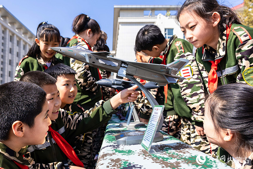 4月10日，呼和浩特市玉泉区五塔寺东街小学“少年军校”学员在观看展示的军事装备模型。丁根厚摄