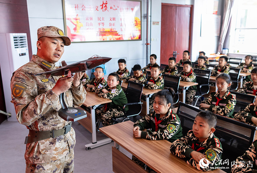 4月10日，呼和浩特市玉泉区人武部工作人员在为五塔寺东街小学“少年军校”学员展示军事装备模型。丁根厚摄