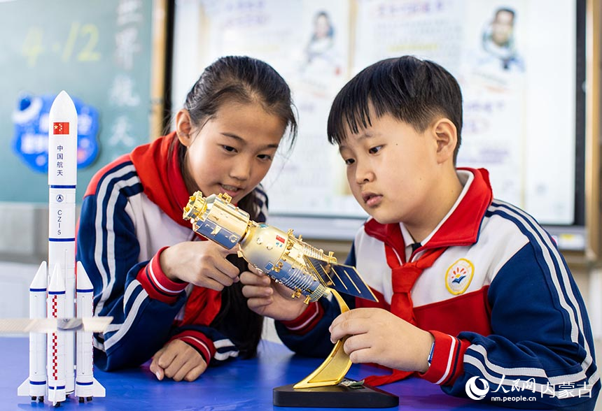 呼和浩特市玉泉区石东路小学学生在世界航天日主题科普活动中近距离观看航天器模型。丁根厚摄