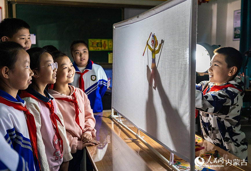 4月22日，呼和浩特市玉泉区小召小学学生在老师的指导下体验皮影戏表演。丁根厚摄