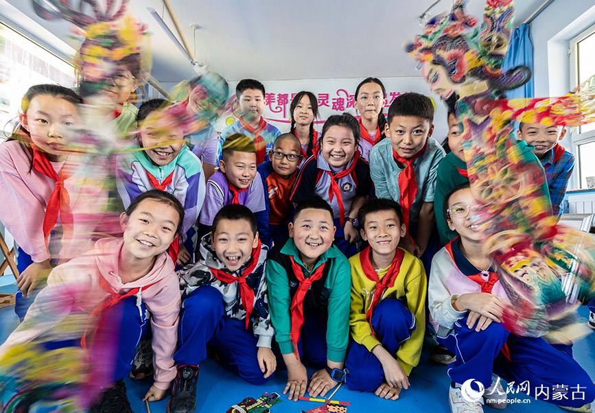 4月22日，呼和浩特市玉泉区小召小学老师在向学生传授皮影的操控表演技巧。丁根厚摄