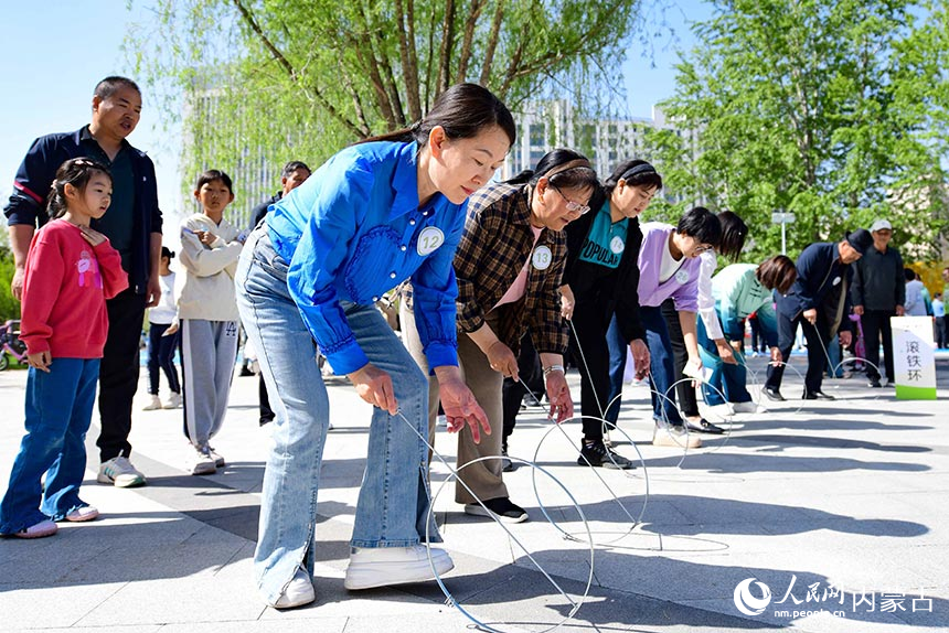 鄂尔多斯市康巴什区学府社区居民在“滚铁环”趣味运动项目比赛中。王正摄