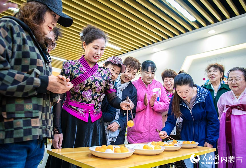 呼和浩特市玉泉区清泉街社区的志愿者和居民在参加“夹乒乓球”趣味游戏。丁根厚摄