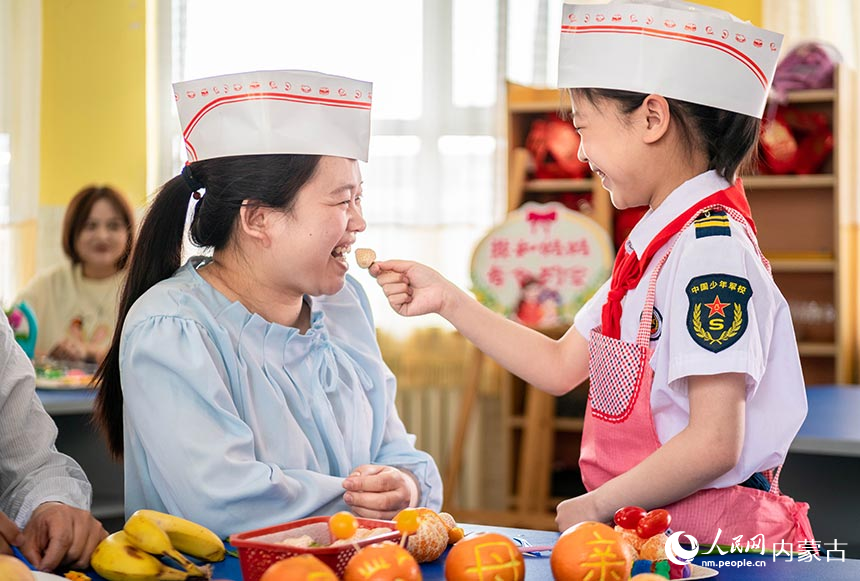 呼和浩特市玉泉区五塔寺东街小学学生请妈妈品尝自己刚刚制作的水果拼盘。丁根厚摄