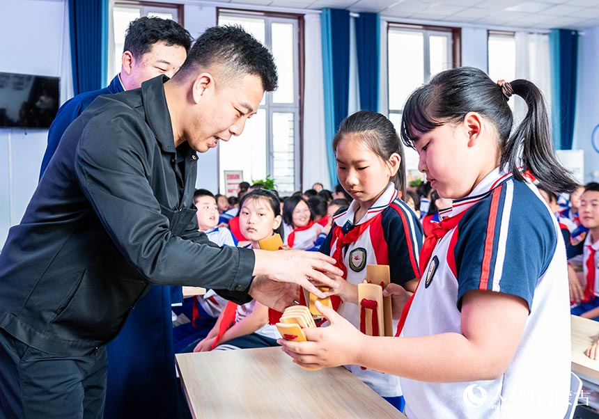 内蒙古曲艺家协会副主席杨钰海（左一）在向孩子们传授快板的表演技艺。丁根厚摄