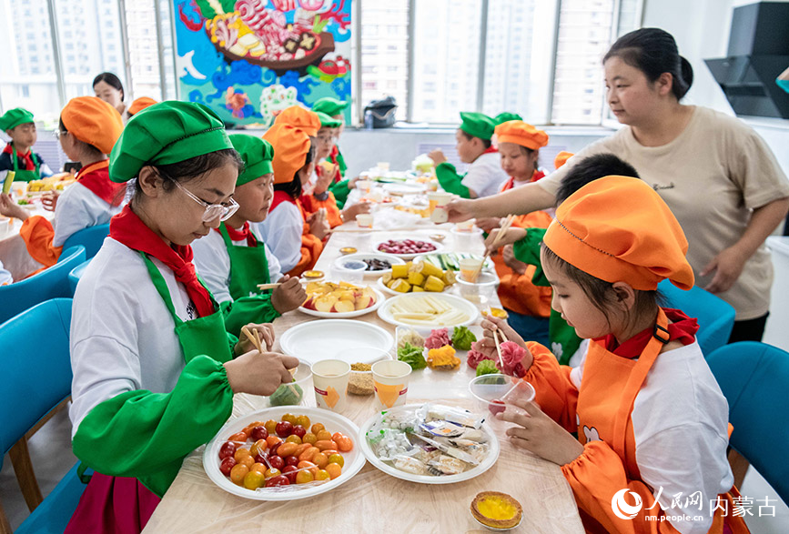 5月24日，呼和浩特市玉泉区南柴火市街小学学生在“烹饪课堂”上品尝烧卖。丁根厚摄