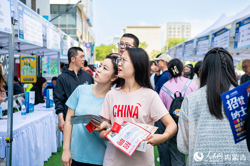 5月25日，求职者在呼和浩特市玉泉区户外大型线下招聘会现场寻找心仪的岗位。丁根厚摄