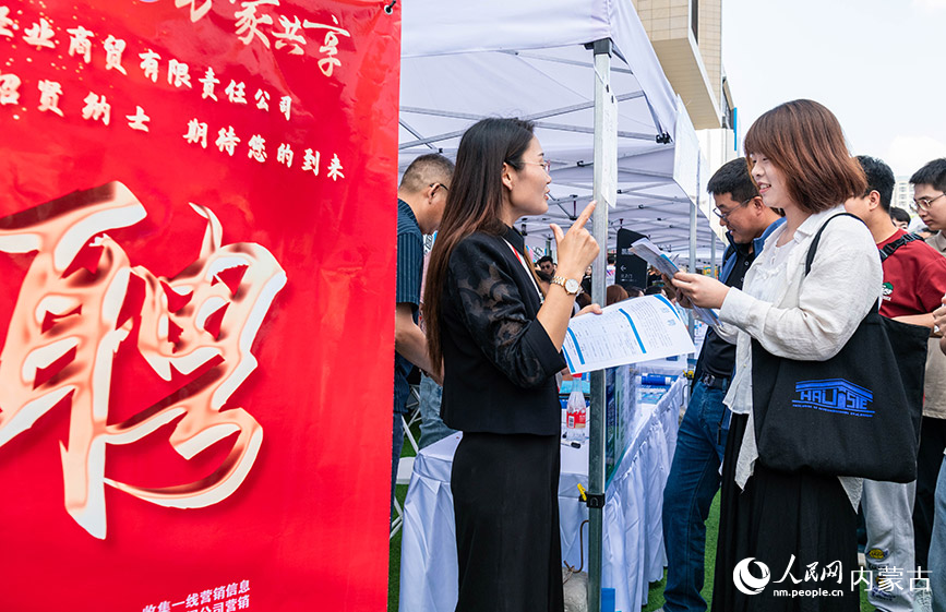 5月25日，求职者（右）在呼和浩特市玉泉区户外大型线下招聘会现场与用人单位交流。丁根厚摄