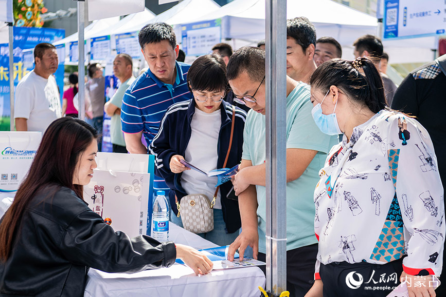 5月25日，求职者在呼和浩特市玉泉区户外大型线下招聘会现场查看招聘信息。丁根厚摄